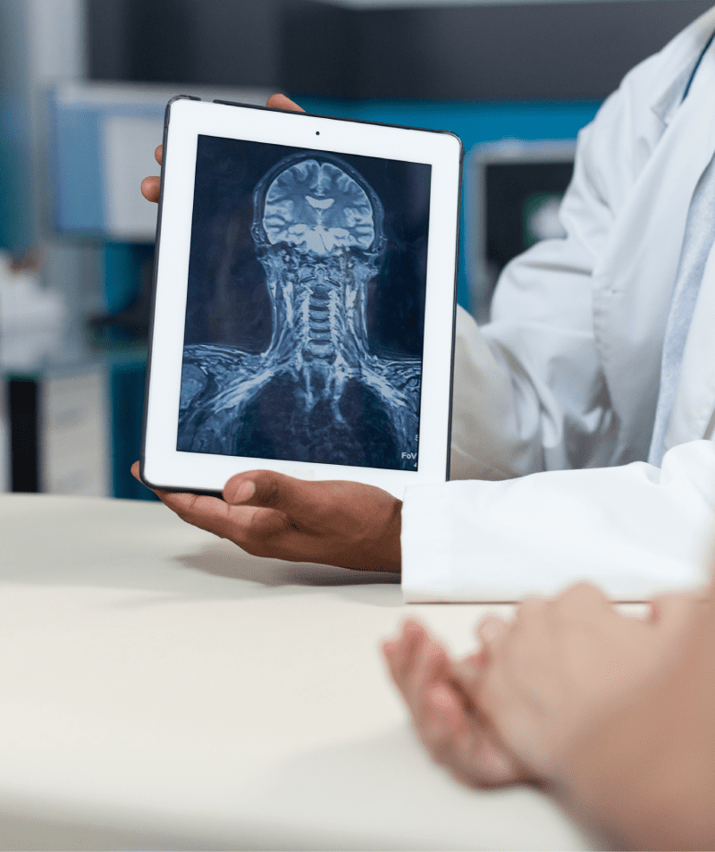 Closeup of african american radiologist holding tablet with bones radiography on screen discussing healthcare treatment with mother during medical consultation. Doctor working in hospital office